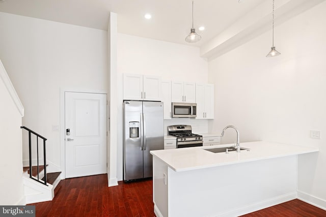 kitchen featuring stainless steel appliances, white cabinetry, sink, hanging light fixtures, and dark wood-type flooring