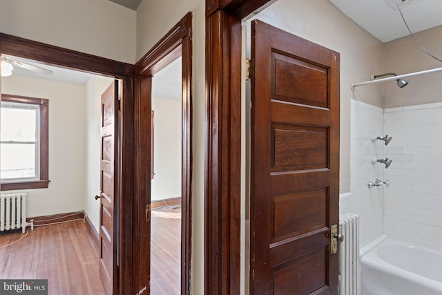 bathroom with hardwood / wood-style floors, radiator, tiled shower / bath, and ceiling fan