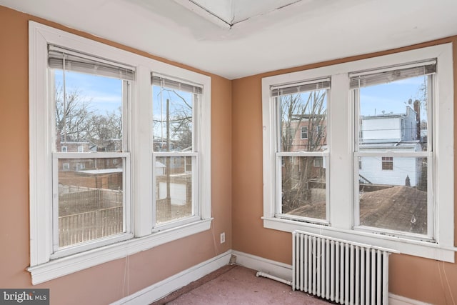 carpeted empty room with radiator and plenty of natural light