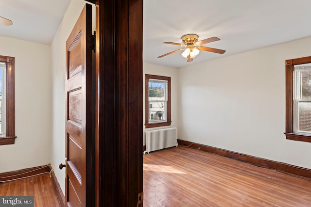 empty room featuring radiator heating unit, wood-type flooring, and ceiling fan