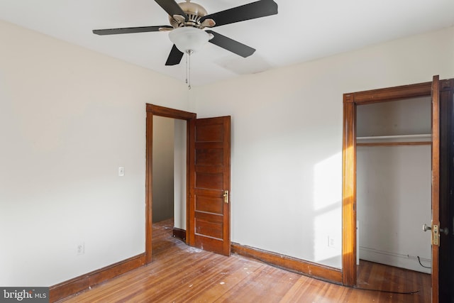 unfurnished bedroom featuring ceiling fan, a closet, and hardwood / wood-style flooring