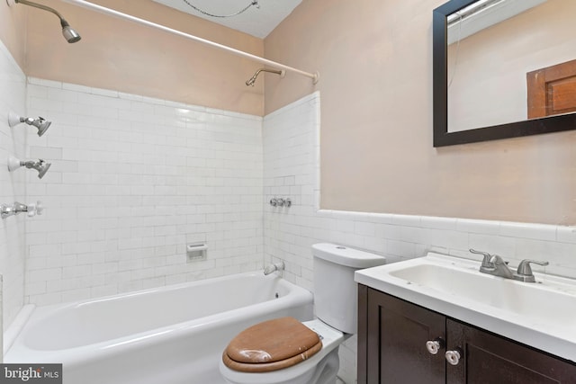 full bathroom with toilet, tiled shower / bath, tile walls, vanity, and decorative backsplash