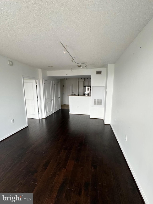 unfurnished living room with dark wood-type flooring, visible vents, and a textured ceiling