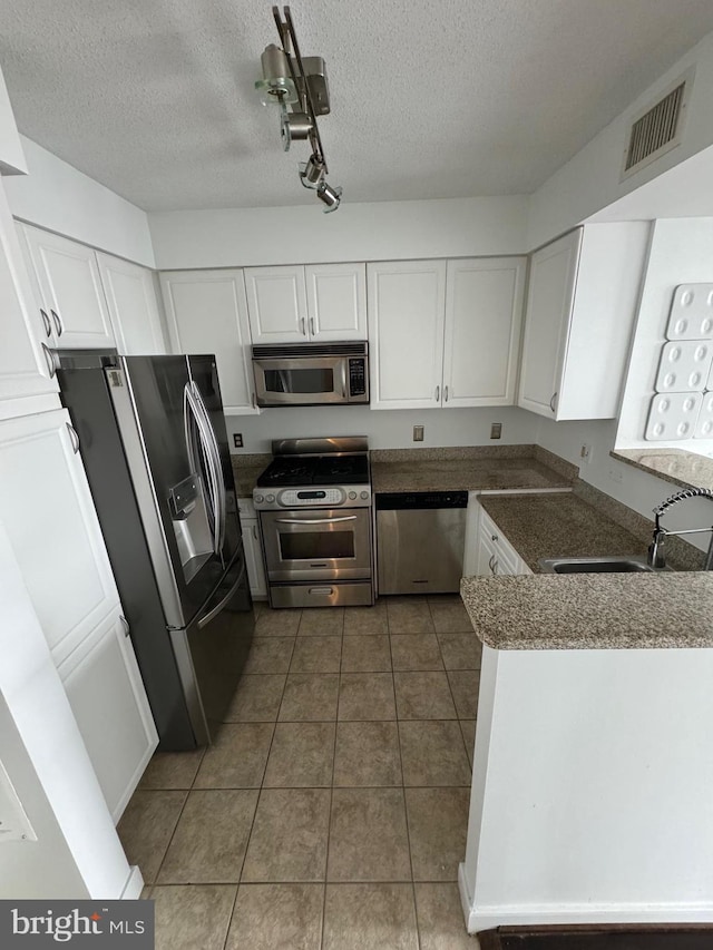 kitchen featuring stainless steel appliances, tile patterned flooring, sink, a textured ceiling, and white cabinets