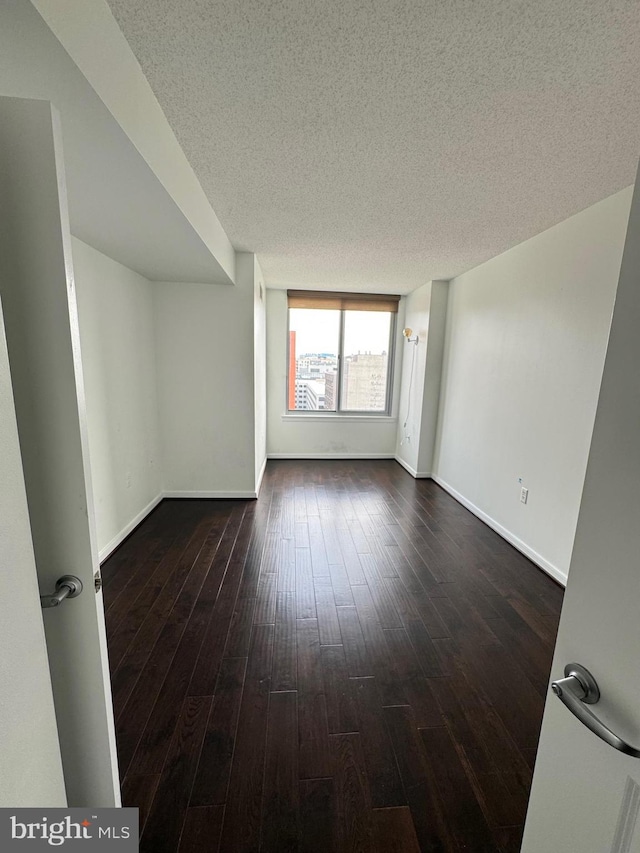 spare room featuring hardwood / wood-style floors and a textured ceiling