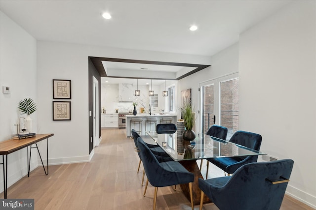 dining room with light hardwood / wood-style floors and a tray ceiling