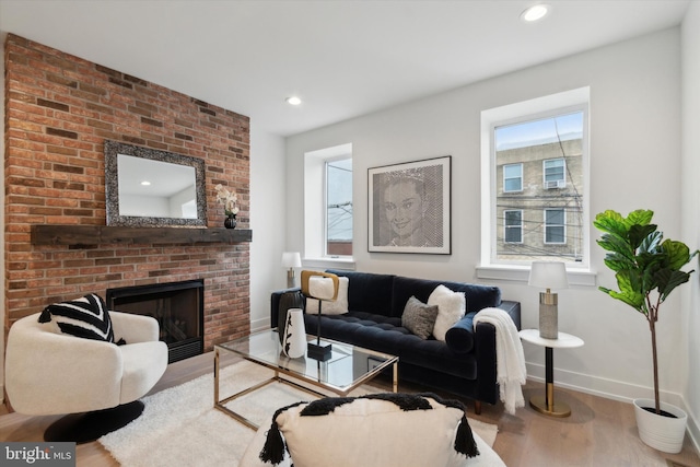 living room with a brick fireplace, hardwood / wood-style flooring, and a healthy amount of sunlight