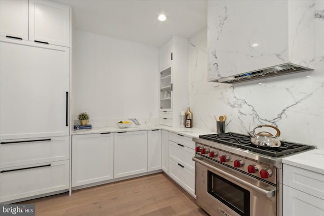 kitchen with decorative backsplash, light hardwood / wood-style flooring, premium range, and white cabinets