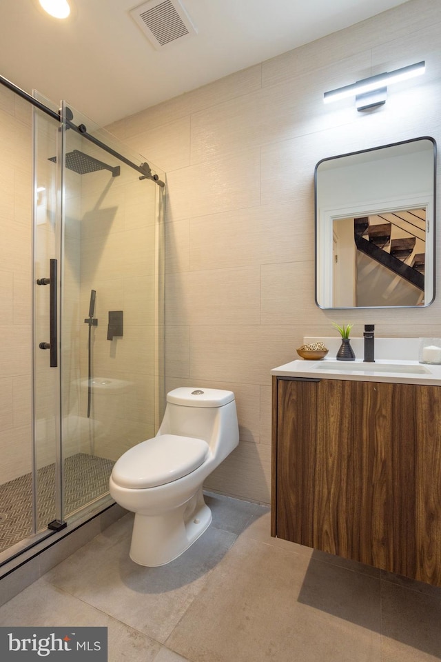 bathroom featuring tile walls, vanity, toilet, and an enclosed shower