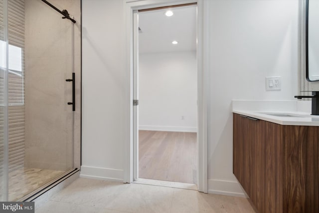 bathroom with wood-type flooring, a shower with shower door, and vanity