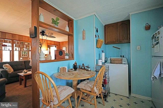 dining space with ornamental molding, wooden walls, washer / dryer, ceiling fan, and light carpet