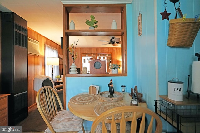 dining room featuring ceiling fan, wooden walls, and carpet floors