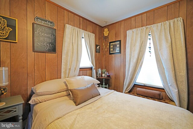 bedroom with wooden walls and multiple windows