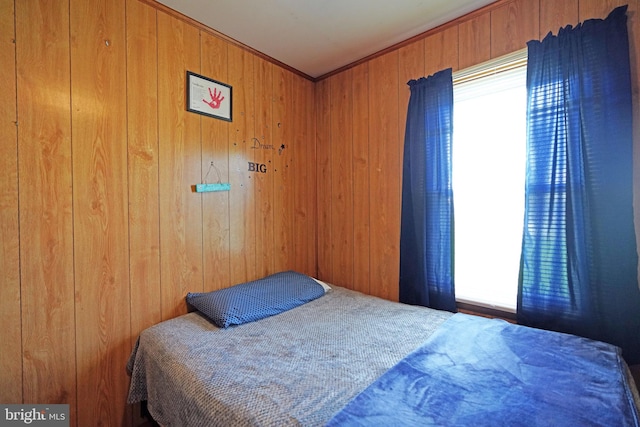 bedroom with multiple windows, wooden walls, and ornamental molding