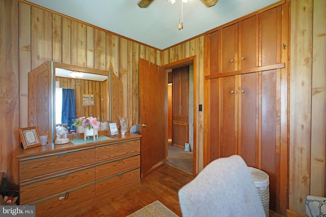 living area with ceiling fan, wood walls, and dark hardwood / wood-style floors