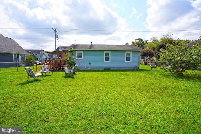 rear view of house with a wooden deck and a lawn