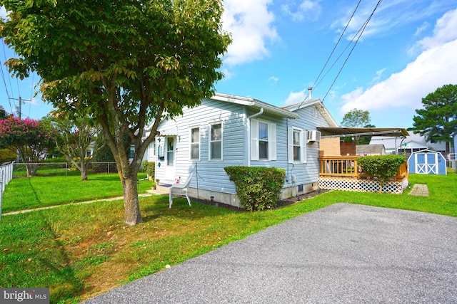 view of home's exterior with a wooden deck, a storage shed, and a lawn