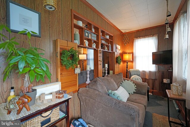 living area with wooden walls, carpet floors, and crown molding