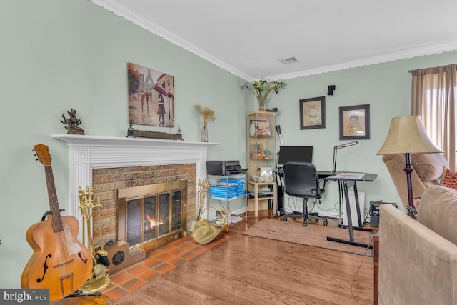 home office with crown molding, a brick fireplace, wood finished floors, and visible vents