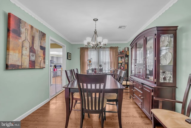 dining space featuring light wood-style floors, a chandelier, and ornamental molding