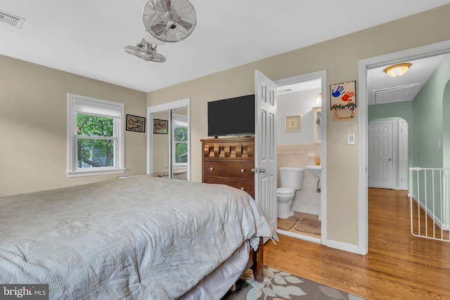 bedroom featuring visible vents, ensuite bath, attic access, and wood finished floors