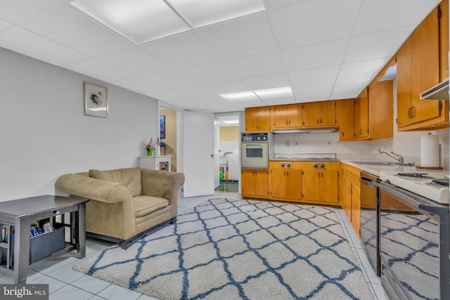 kitchen with tasteful backsplash, under cabinet range hood, light countertops, white appliances, and a sink