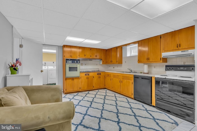 kitchen featuring black dishwasher, under cabinet range hood, range with electric stovetop, white oven, and washer and clothes dryer