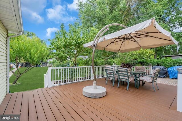 deck featuring outdoor dining area and a lawn