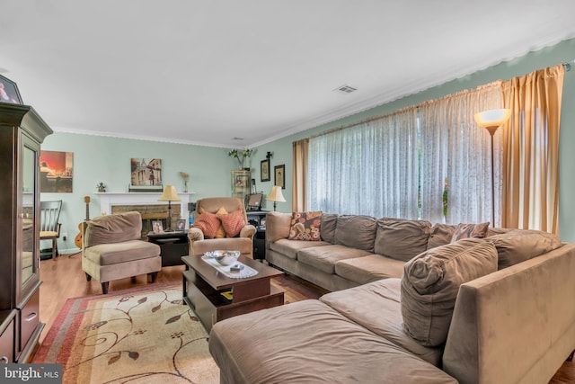 living area featuring visible vents, a fireplace, crown molding, and wood finished floors