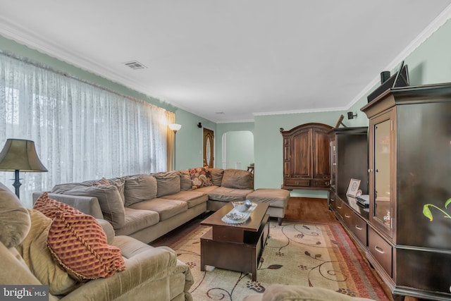 living room featuring crown molding, arched walkways, visible vents, and light wood-type flooring