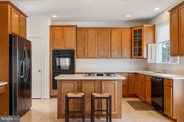 kitchen featuring a breakfast bar, sink, black appliances, a center island, and light tile patterned flooring