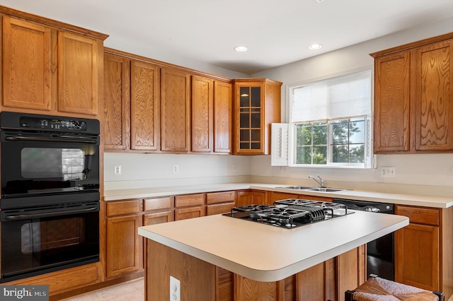 kitchen featuring glass insert cabinets, a kitchen breakfast bar, light countertops, black appliances, and a sink