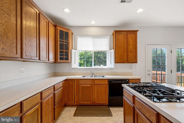 kitchen with sink, light tile patterned floors, black dishwasher, and a wealth of natural light