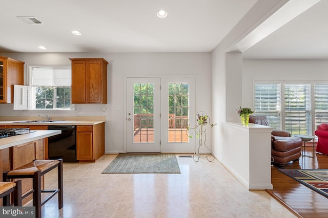 kitchen featuring black dishwasher, light hardwood / wood-style flooring, and a wealth of natural light