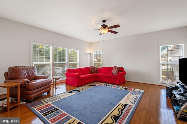 living room featuring ceiling fan, baseboards, and wood finished floors