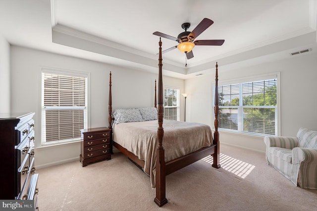 bedroom featuring light carpet, baseboards, visible vents, a tray ceiling, and crown molding