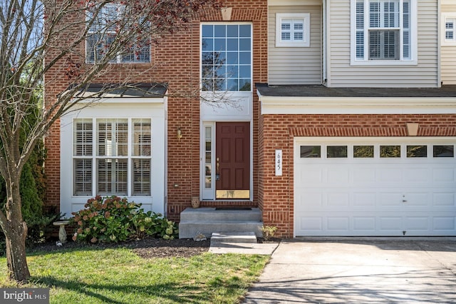 property entrance with a garage, concrete driveway, and brick siding