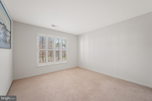 unfurnished room with light carpet, visible vents, and baseboards