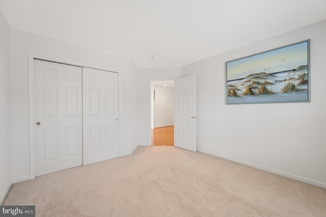 unfurnished bedroom with light carpet and a closet