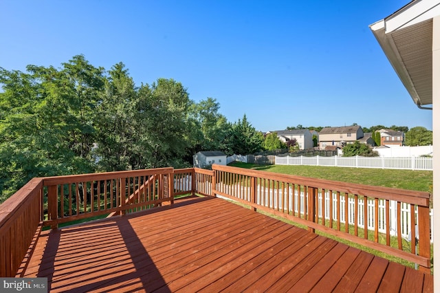 deck featuring a lawn, a storage shed, a residential view, a fenced backyard, and an outdoor structure