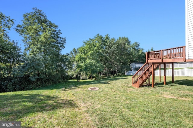 view of yard featuring a deck, stairway, a fire pit, and fence