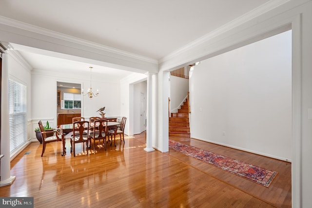 dining room featuring stairs, ornamental molding, wood finished floors, and ornate columns