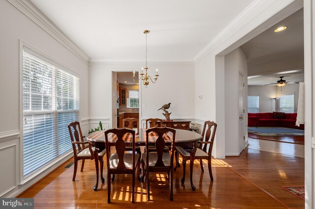 dining area featuring ceiling fan with notable chandelier, crown molding, and wood-type flooring