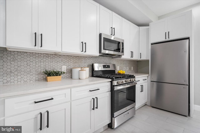 kitchen with white cabinetry, appliances with stainless steel finishes, decorative backsplash, and light stone countertops