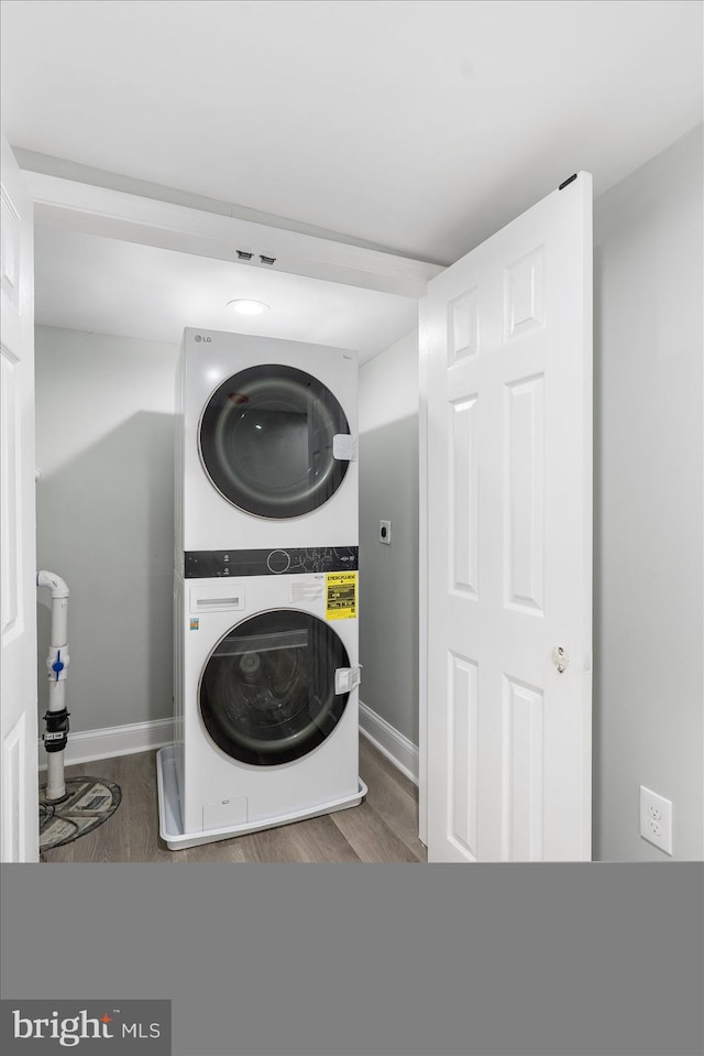 washroom featuring stacked washer and clothes dryer and hardwood / wood-style flooring