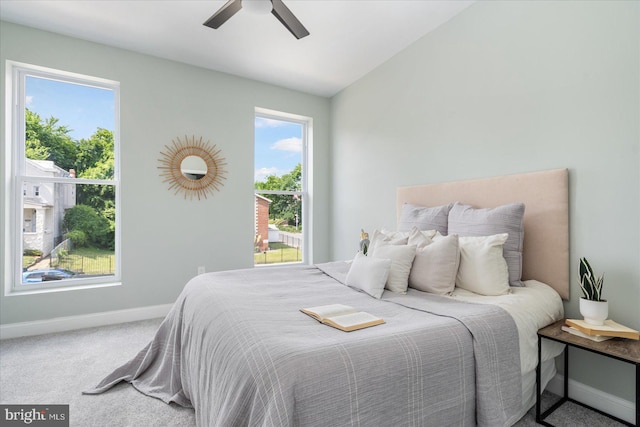 carpeted bedroom with ceiling fan, multiple windows, and lofted ceiling