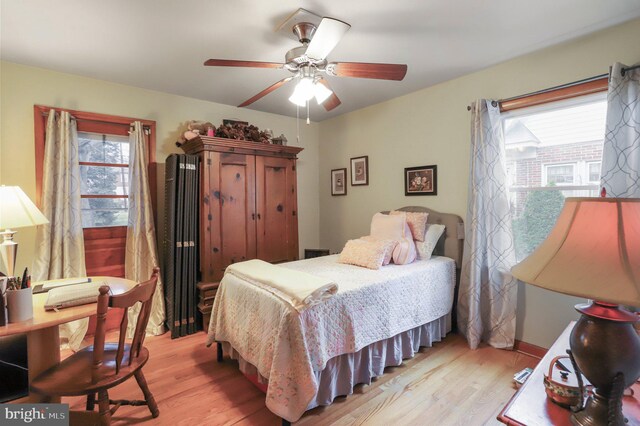 bedroom featuring light hardwood / wood-style flooring, ceiling fan, and multiple windows