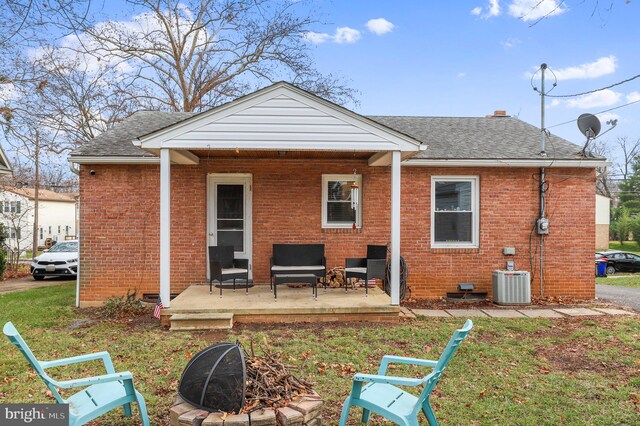 rear view of property with central air condition unit and an outdoor fire pit