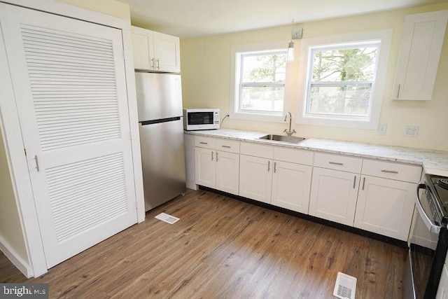 kitchen featuring dark wood-type flooring, white cabinets, light stone counters, sink, and stainless steel appliances