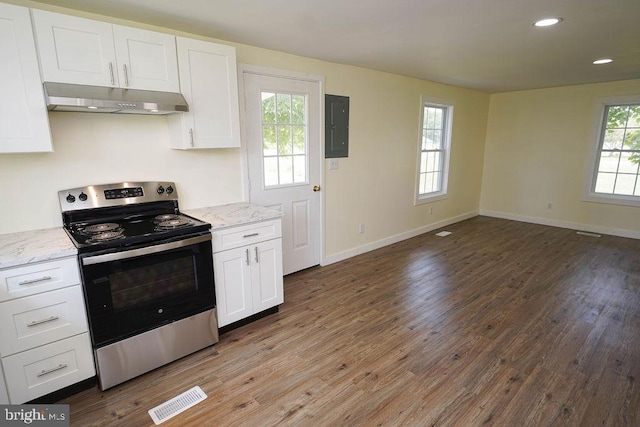 kitchen featuring stainless steel electric stove, wood-type flooring, light stone counters, electric panel, and white cabinetry